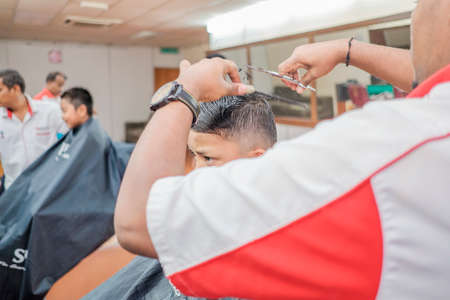 Muadzam Shah, Malaysia - August 14th, 2017 : Little boy getting warber while sitting haircut on chair at barbershop.のeditorial素材