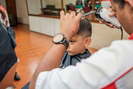 Muadzam Shah, Malaysia - August 14th, 2017 : Little boy getting warber while sitting haircut on chair at barbershop.のeditorial素材