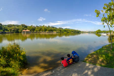 Putrajaya, Malaysia â September 24th, 2017 : Young girl with her young brotherS feeding carps in tropical pond at Wetland Putrajaya.のeditorial素材