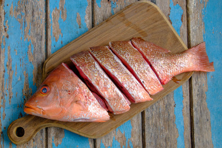 Fresh red snapper on wooden cutting board .