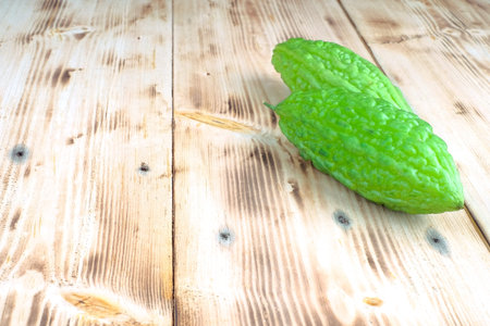 Fresh bitter melon or bitter gourd (Momordica charantia)  over pine wood grain