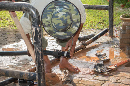 Muadzam Shah, Malaysia â February 8th, 2018  : Two workers install new HDPE pipes under the interlocking bricks walkway without any safety equipment like helmet or boots.の写真素材