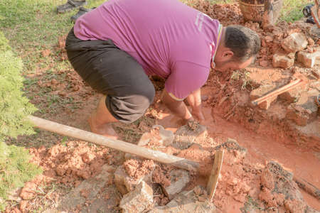 Muadzam Shah, Malaysia  February 8th, 2018  : Pipe contractor repairing leaking under the interlocking bricks walkway without any safety equipment like helmet or boots.のeditorial素材