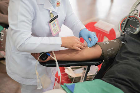 Unidentified hospital staff arms sticking needle into male arm during blood donation campaign .のeditorial素材