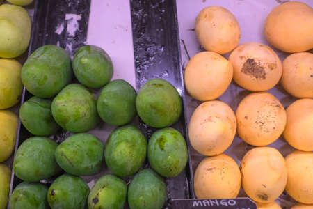 Fresh yellow and green raw manggoes display for sale at marketの写真素材