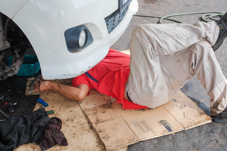 Muadzam Shah , Malaysia - December 28th, 2017 :  Mechanic in red shirt  lying down and working under...