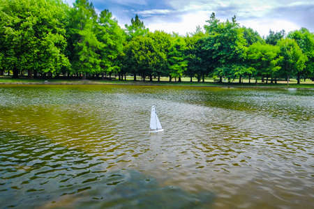 Radio controlled model sailboat on lake being launched by senior citizen in in Christchurch Botanic Garden , New Zealand.の写真素材