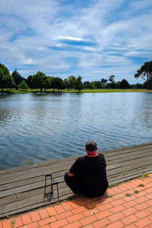 Christchurch, New Zealand  December 18th, 2017 : Senior man with radio controlled model sailboat on lake being launched by senior citizen  in Christchurch Botanic Garden , New Zealand.のeditorial素材