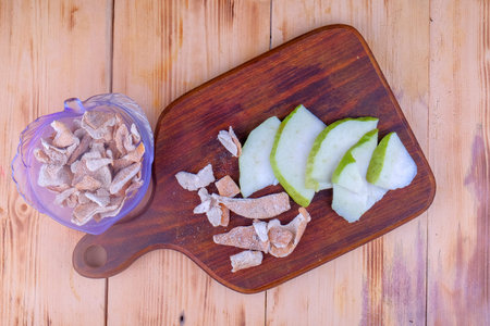 Sour orange peel and sliced guava on cutting board.