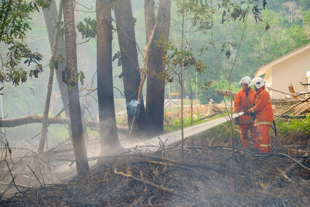 Muadzam Shah, Malaysia - May 7th, 2018: Two firemen wearing safety helmet spraying water to fire...