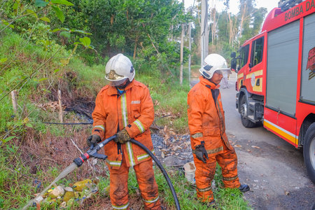 Muadzam Shah, Malaysia - May 7th, 2018: Two firemen wearing safety helmet spraying water to fire...