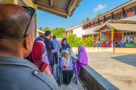 Muadzam Shah, Malaysia - May 9th, 2018: An unidentified wheelchair bound Malaysian senior citizen being assisted to cast a vote during 14th General Election on May 9, 2018, in Muadzam Shah, Malaysia.のeditorial素材