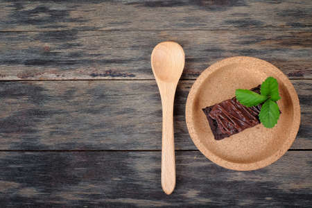 Wooden spoon and chocolate brownie with melted chocolate on a wooden plateの写真素材