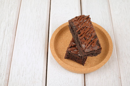 Chocolate brownie with melted chocolate on a wooden plate