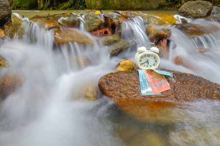 Time is money concept with money and alarm clock on river  .