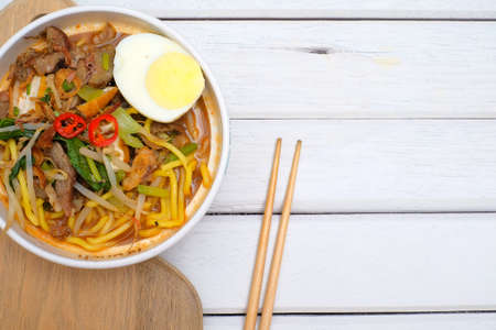 Mee Rebus in the bowl  with chopsticks on white table This dish is made of noodles ,vegetable,egg with a spicy .の写真素材