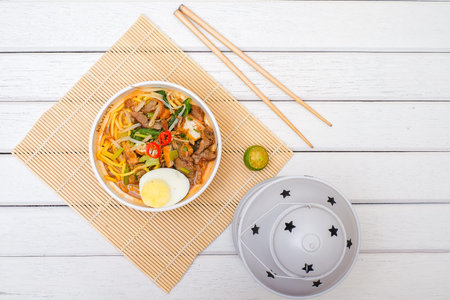 Malay Mee Rebus in the bowl  with chopsticks on white table This dish is made of noodles...