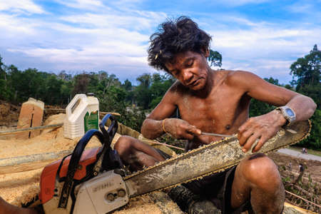 Muadzam Shah, Malaysia - 8 September 2018 : Unidentified  timber workers sharpened the chainsaws using chainsaw file  near the jungleのeditorial素材