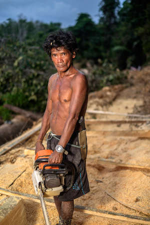 Muadzam Shah, Malaysia - 8 September 2018 : Unidentified man woodcutter cutting wood timber logs. He using a gasoline engine chainsaw as a main tool.のeditorial素材
