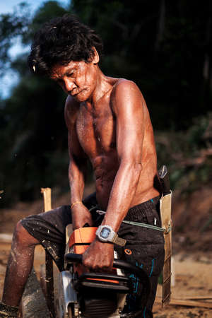 Muadzam Shah, Malaysia - 8 September 2018 : Unidentified man woodcutter cutting wood timber logs. He using a gasoline engine chainsaw as a main tool.のeditorial素材