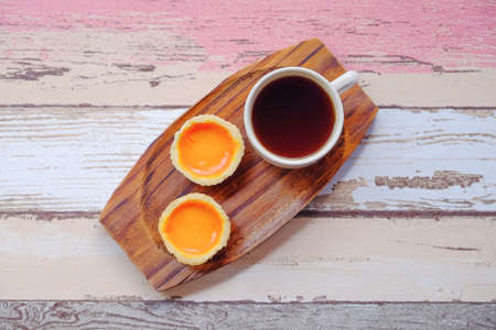 Egg tart and a cup of coffee on wooden backgroundの写真素材