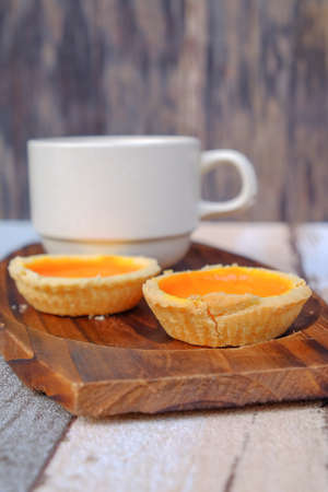 Egg tart and a cup of coffee on wooden backgroundの写真素材