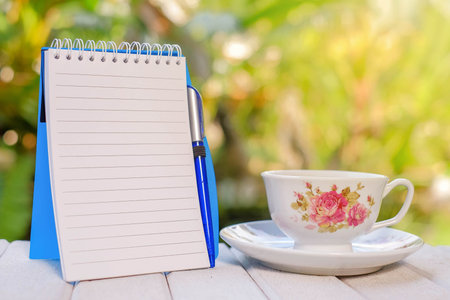 Cup of coffee, open notebook with blank pages, pen,  on green background  Still life, concept of...