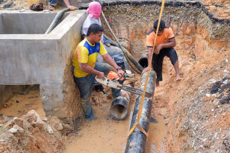 Muadzam Shah, Malaysia - November 1st, 2018  : Worker using chainsaw to cut water pipe in new construction site.のeditorial素材