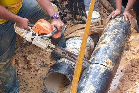 Muadzam Shah, Malaysia - November 1st, 2018  : Worker using chainsaw to cut water pipe in new construction site.のeditorial素材