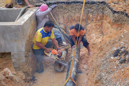 Muadzam Shah, Malaysia - November 1st, 2018  : Worker using chainsaw to cut water pipe in new construction site.のeditorial素材