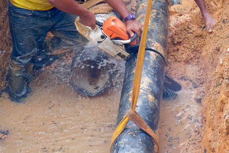 Muadzam Shah, Malaysia - November 1st, 2018  : Worker using chainsaw to cut water pipe in new construction site.のeditorial素材
