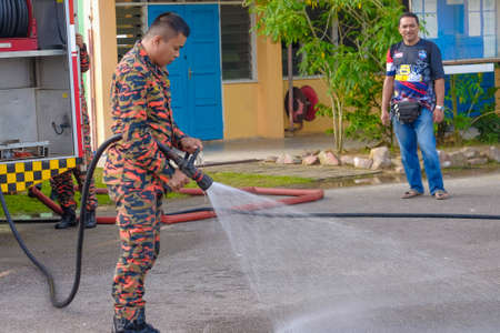 Muadzam Shah, Malaysia -  November 24th  , 2018 : Fireman flushes water towards Muadzam Shah's children at a mass circumcision ceremony in the yard of  school during long break of school holiday.のeditorial素材