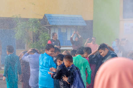 Muadzam Shah, Malaysia -  November 24th  , 2018 : Fireman flushes water towards Muadzam Shah's children at a mass circumcision ceremony in the yard of  school during long break of school holiday.のeditorial素材