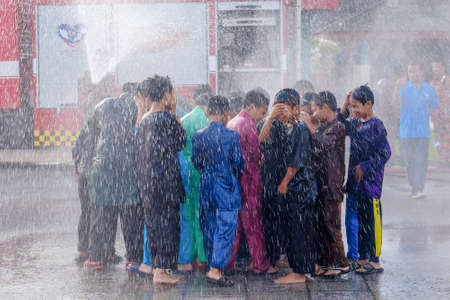 Muadzam Shah, Malaysia -  November 24th  , 2018 : Fireman flushes water towards Muadzam Shah's children at a mass circumcision ceremony in the yard of  school during long break of school holiday.のeditorial素材