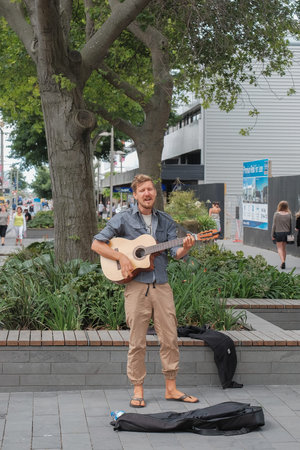 Christchurch, New Zealand - Disember 19th, 2017 : A lone busker plays guitar and sings  at...