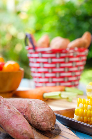 Cherry tomatoes, sweet potato, corn and baby carrot on wooden background