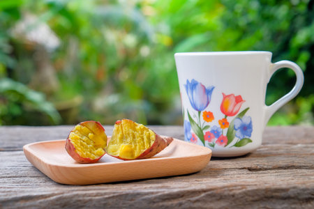 A cup of tea and red sweet potato on wooden plate over rustic wooden table