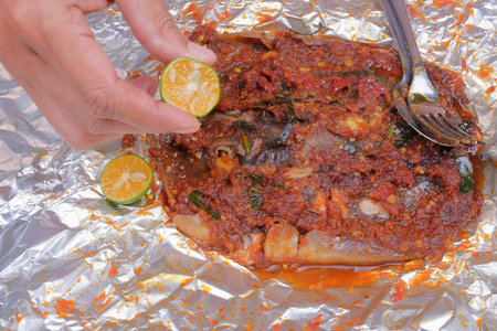 Men squeeze the lime while eating roasted stingrays with hot spicy in aluminum foil