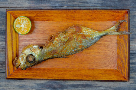 Fried fish and lemon slices in a wooden plate
