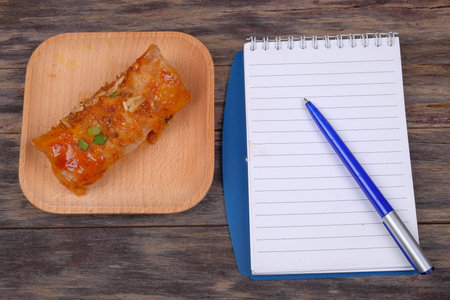Opened notebook with pen and Popia- Malaysian traditional dessert, filed with bean sprouts, nuts and...