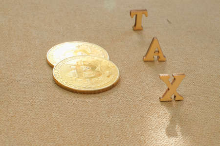 Bitcoin  and next to wooden with TAX letters. Bitcoin taxation conceptの写真素材