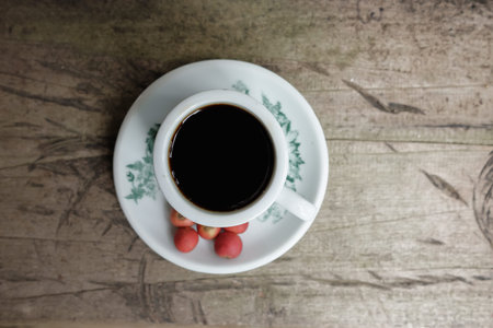 Hot coffee vintage cup with fresh organic red coffee beans on the wooden table