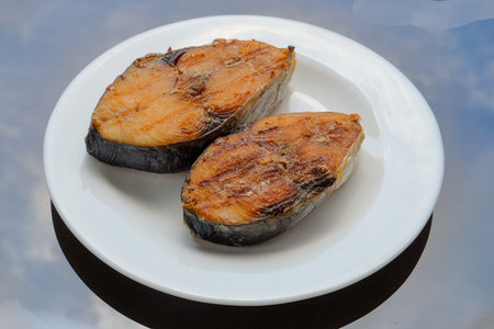 A grilled mackerel fish on white plate is a one of the Malaysian people favorite dish