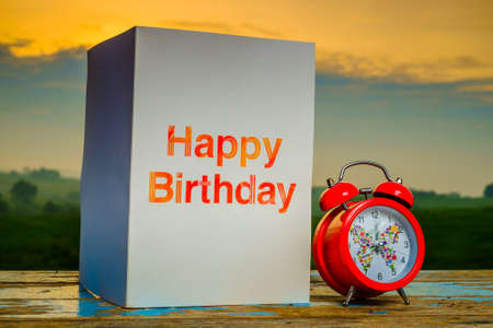 Mini supermarket shopping cart , alarm clock and coins on old wood with blurred green nature background  and beautiful  sunrise.の写真素材