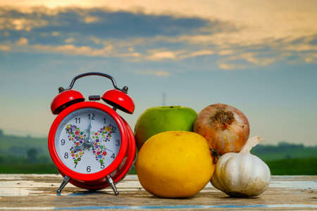 Garlic, lemon, alarm clock   and green apple on old wooden with blurred background , healthy nutrition, strengthening immunity and treatment of fluの写真素材