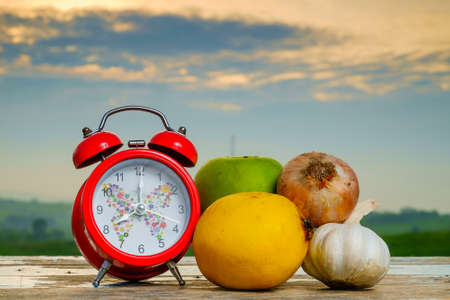 Garlic, onion, lemon, alarm clock   and green apple on old wooden with blurred background , healthy nutrition, strengthening immunity and treatment of fluの写真素材