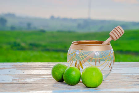 Glass jar, honner dipper and Limes  on old wooden with blurred background ,healthy nutrition,strengthening immunity and dietの写真素材