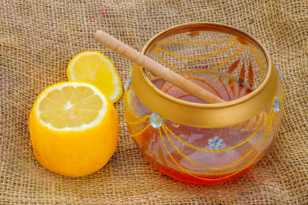 Close-up of lemon and jar with honey and dipper on jute. Healthy eatingの写真素材