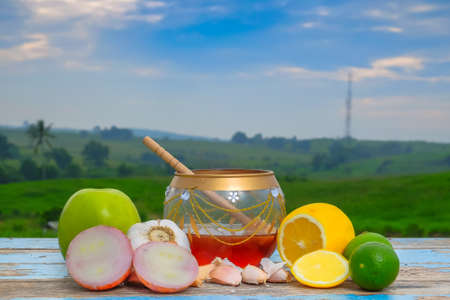 Fresh honey in glass jar , garlic, onion, lime,  lemon and green apple on old wooden with blurred background . Healthy nutrition and strengthening immunityの写真素材