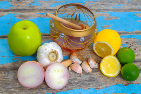 Fresh honey in glass jar , garlic, lemon and green apple on old wooden with blurred background . Healthy nutrition and strengthening immunity .の写真素材